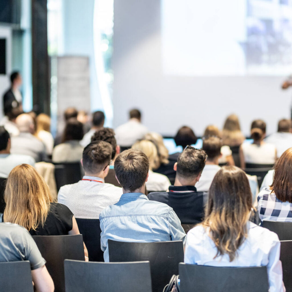 Audience at the conference hall. Male speaker giving a talk in conference hall at business event. Business and Entrepreneurship concept. Focus on unrecognizable people in audience.